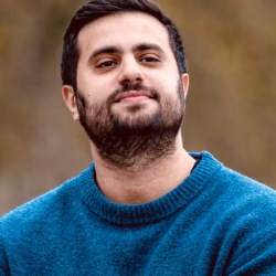 Headshot of writer Abdelrahman Elgendy smiling at the camera in a blue sweater.
