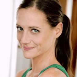 Headshot of Scholar of Note Brenda Withers. She is looking at the camera with her long hair in a ponytail in a green tank top in front of a blurred background.
